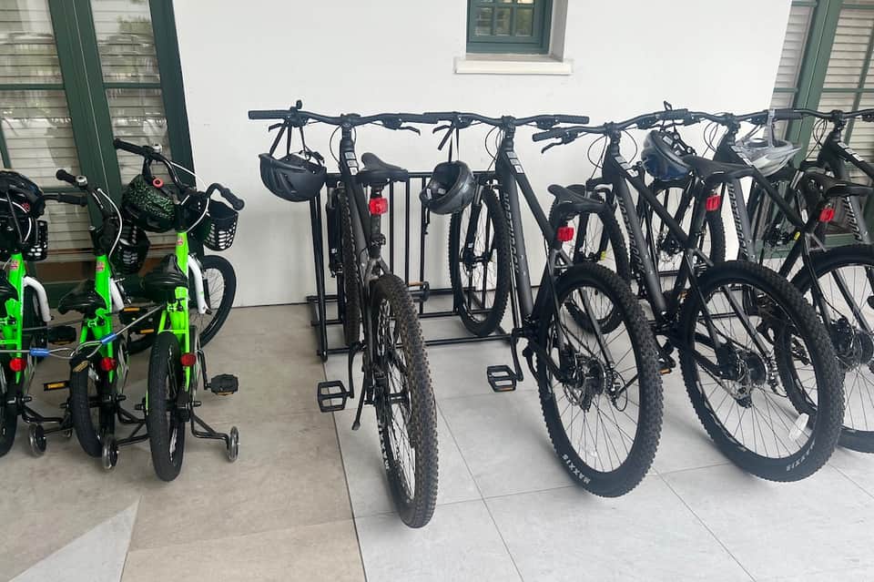 Bike storage and rental area with multiple bicycles and tricycles mounted on organized racks outside building