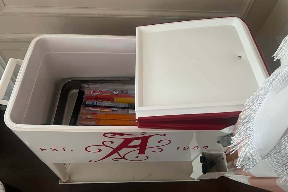 Open white cooler with red accents containing board games and beverages