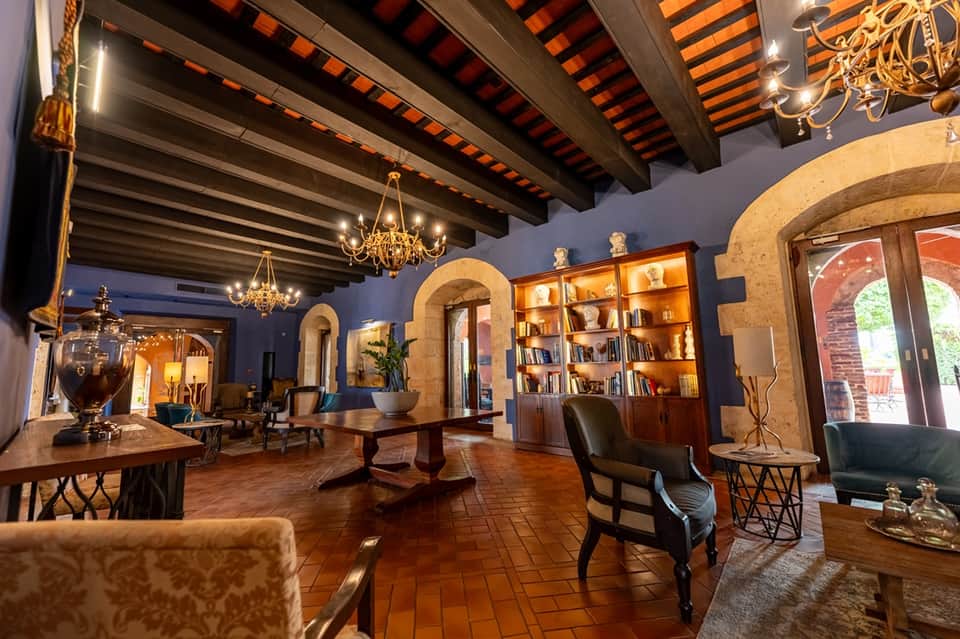 Grand hotel lobby with exposed wooden beams, chandeliers, archways, and elegant furniture arrangement