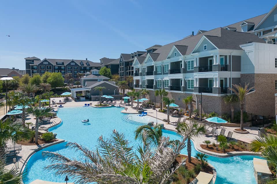 Aerial view of sprawling resort with multiple pools, colorful townhouses, and palm trees