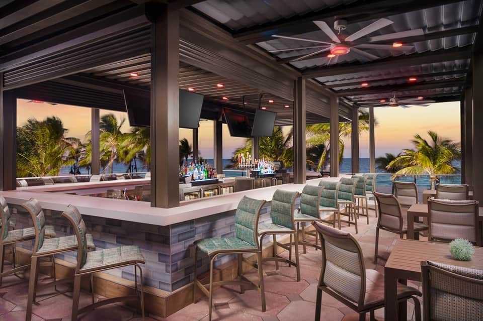 Upscale beachfront bar and lounge with ocean views and palm trees