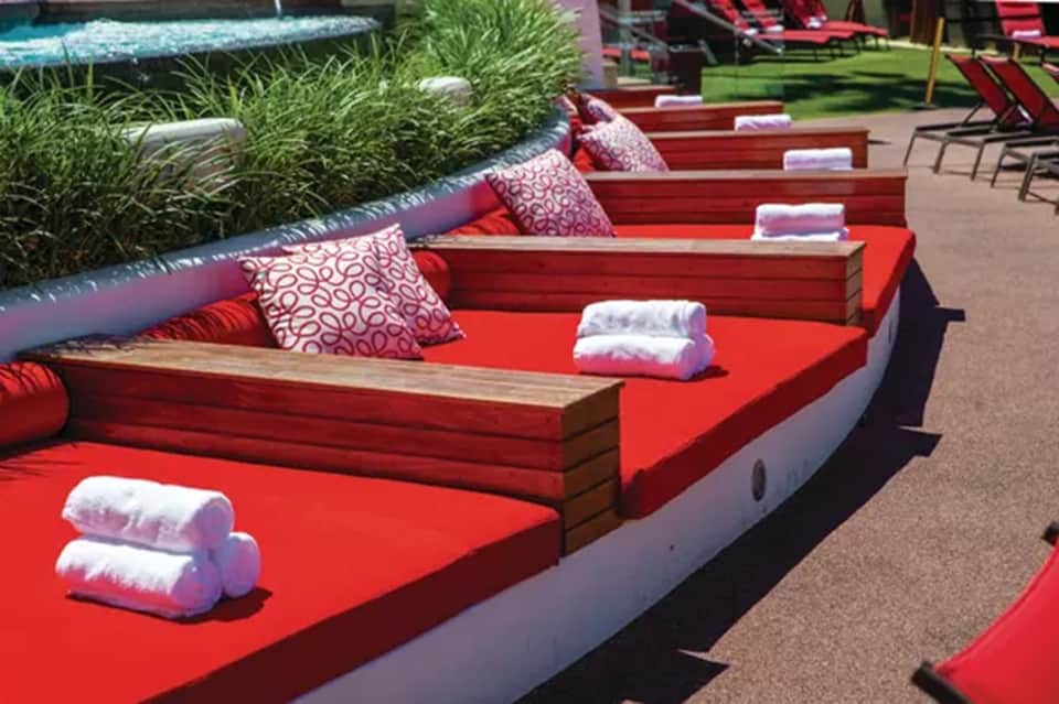 Red waterfront loungers with pillows and white towels overlooking canal
