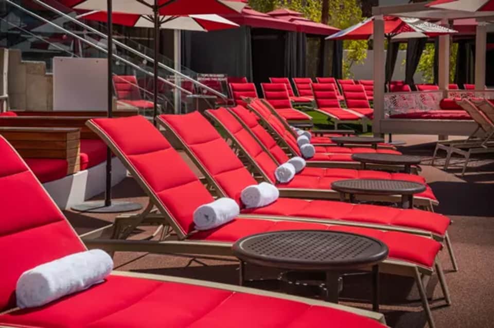Poolside lounge area with red cushioned chairs, red umbrellas, and modern architecture