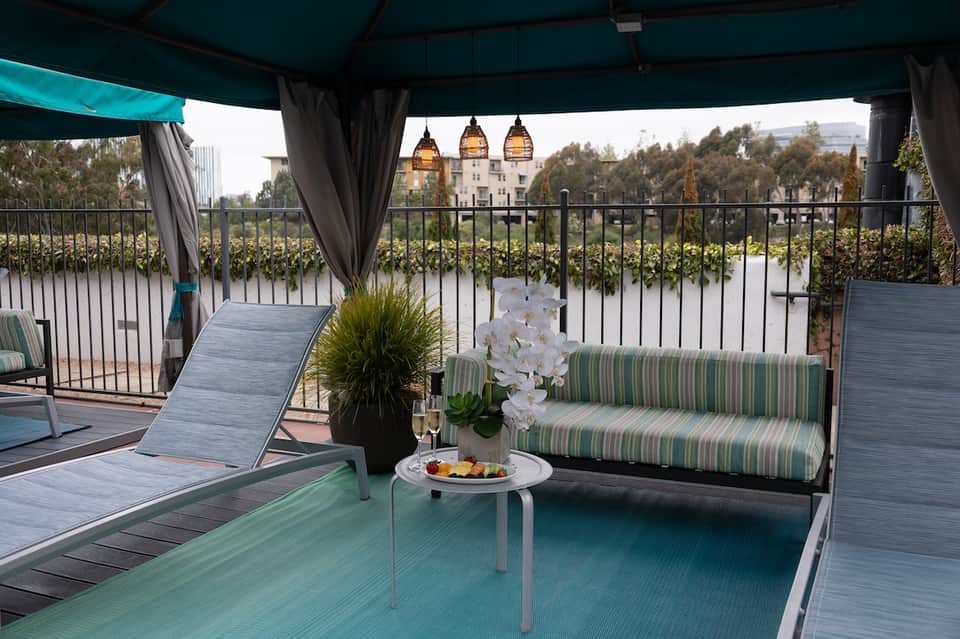 Covered patio with loungers overlooking vineyard and castle under string lights