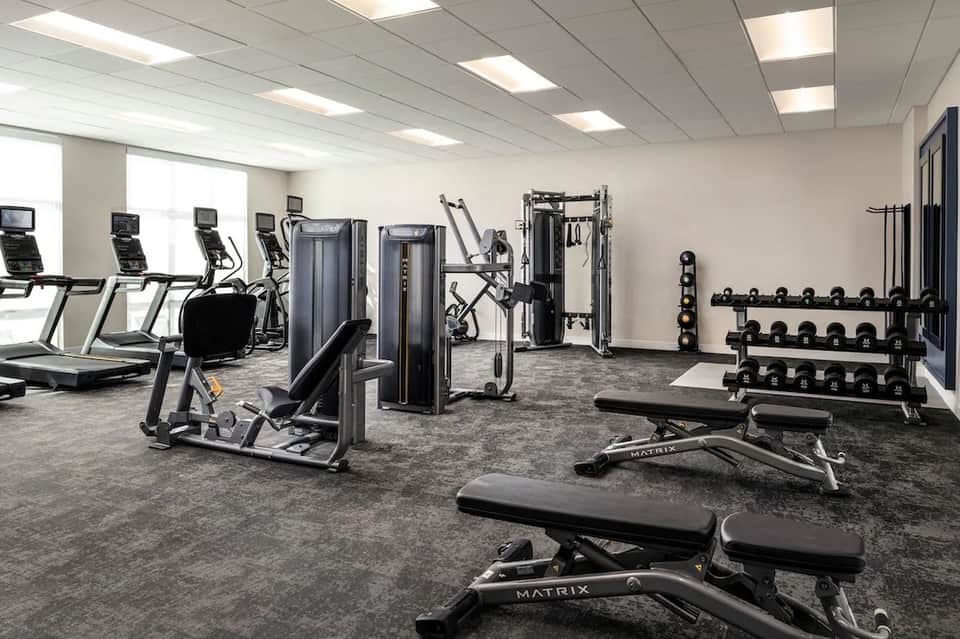 Fully equipped fitness center with cardio machines, weight equipment, and natural lighting