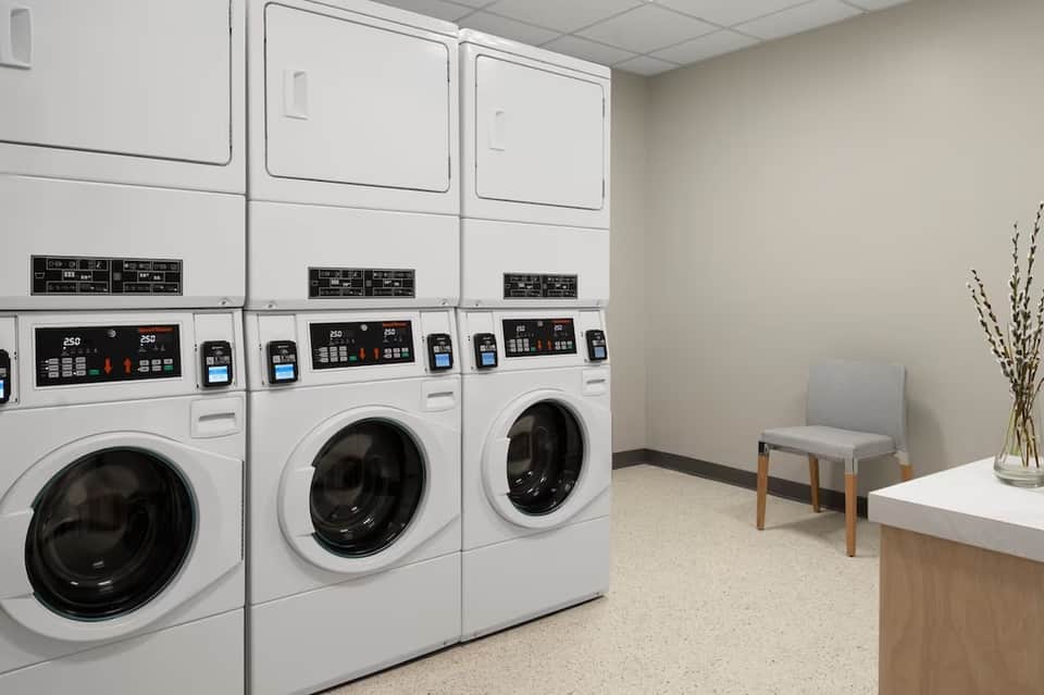 Laundry room with stacked commercial washers, dryers, and waiting seating