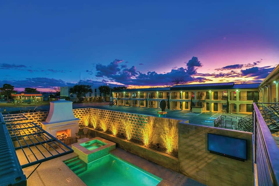 Resort pool terrace at twilight with green spa pool, fire pit, and illuminated walls