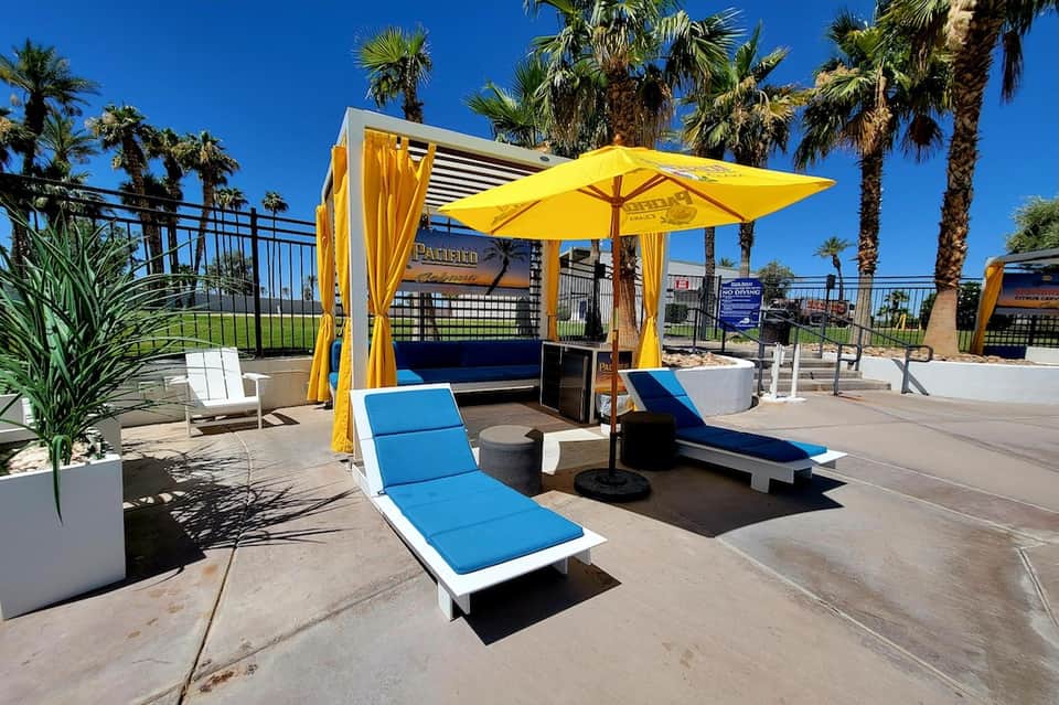 Luxury resort cabana area with yellow umbrellas, blue loungers, and ocean view with palm trees