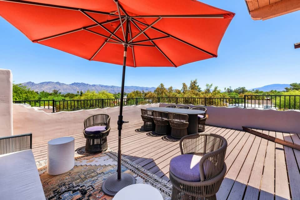 Rooftop terrace with red umbrella, lounge seating, and mountain valley views