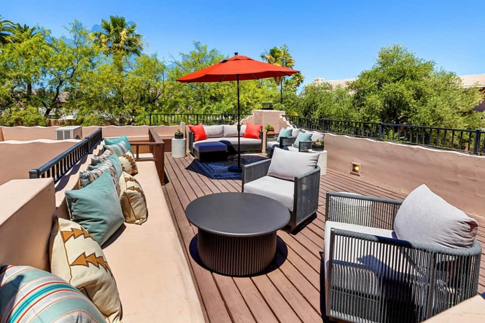 Rooftop deck with lounge seating, red umbrella, and desert mountain views
