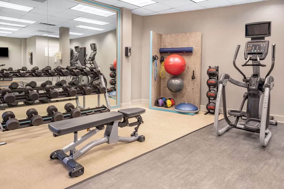 Fitness center with free weights, cardio machines, exercise balls, and mirrors