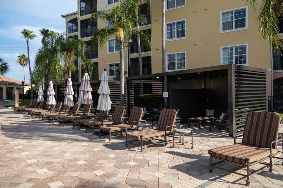 Resort pool area with white umbrellas, striped loungers, and modern building exterior
