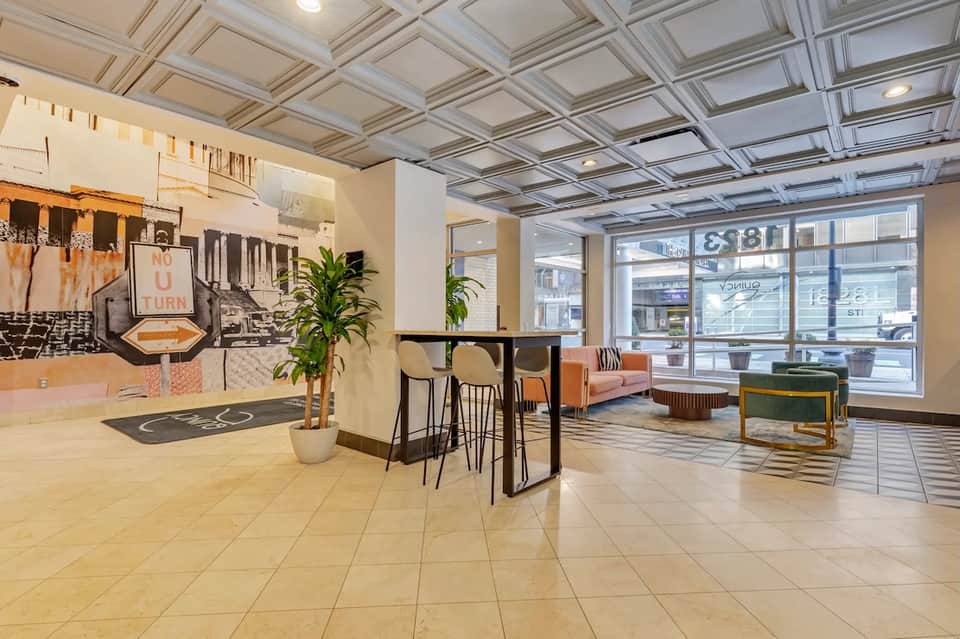 Contemporary hotel lobby with coffered ceiling, bar area, and street-facing windows