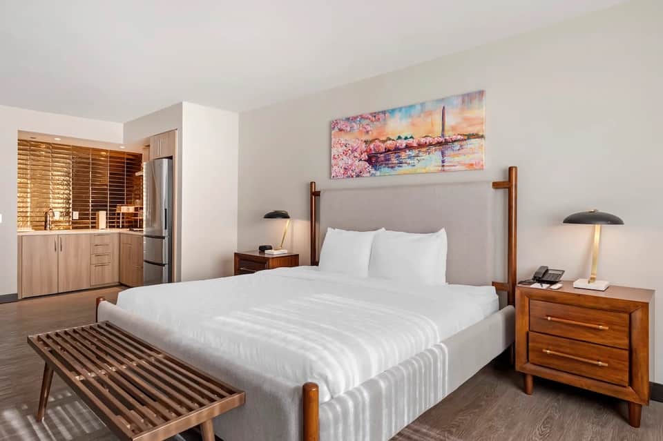 Spacious hotel suite with king bed, wood furnishings, kitchenette, and modern amenities