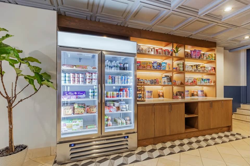 Hotel gift shop with refrigerated cases, illuminated wood shelving displaying merchandise