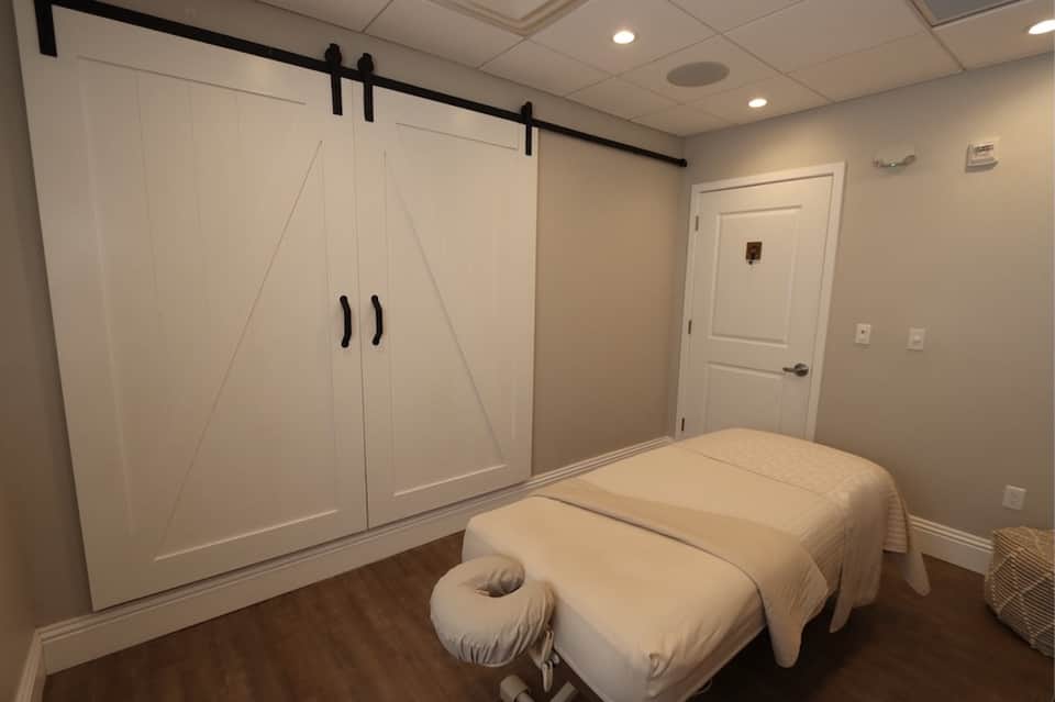 Spa massage room with two treatment beds and white barn doors with black sliding hardware