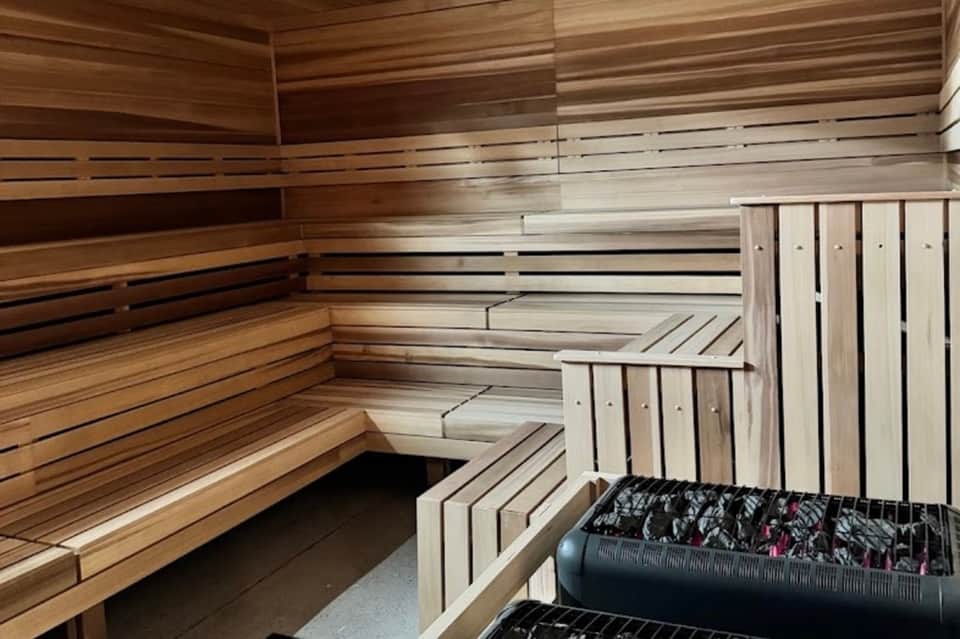Wooden sauna interior with tiered benches, light and dark wood construction, and relaxation space
