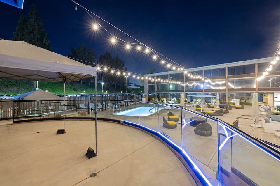 Resort pool deck at night with string lights, modern architecture, and lounge area