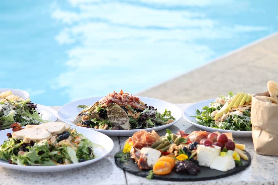 Poolside dining with fresh salads and seafood plates overlooking water
