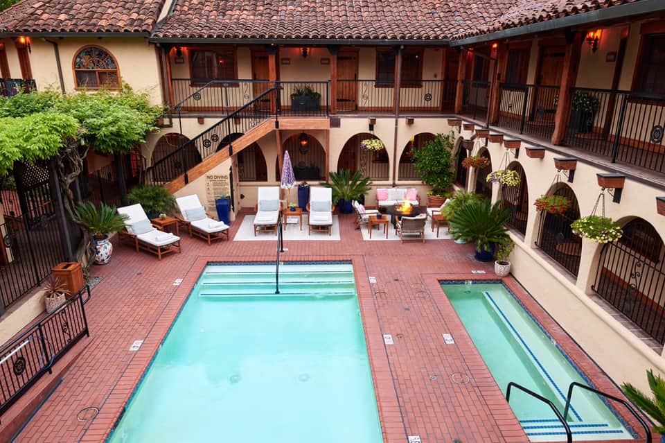 Courtyard-style resort pool with lap lanes, lounge seating, Spanish colonial architecture, and plant décor