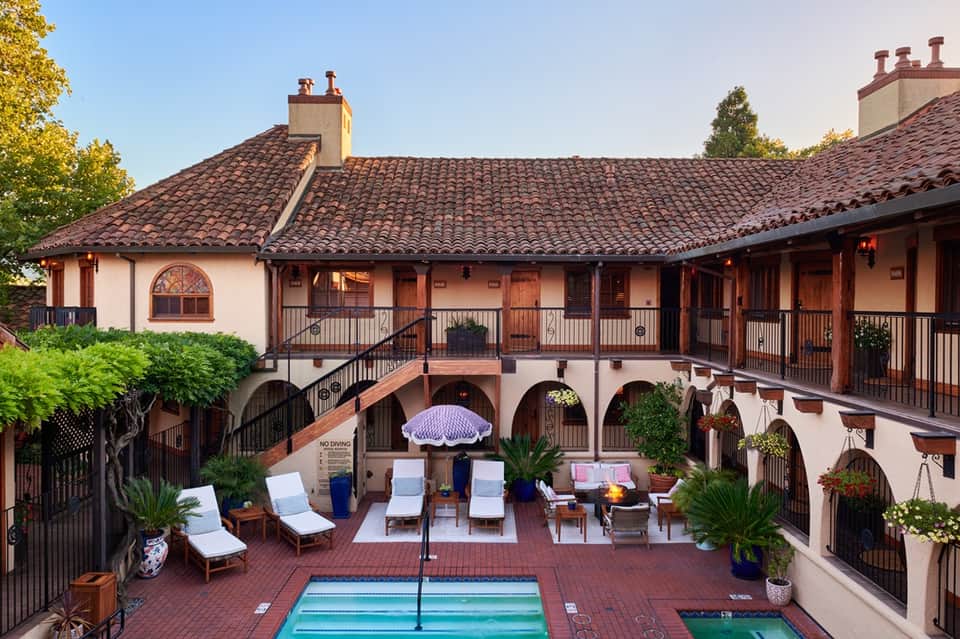 Spanish colonial style courtyard with terracotta tiles, arches, lounge chairs, and small pool