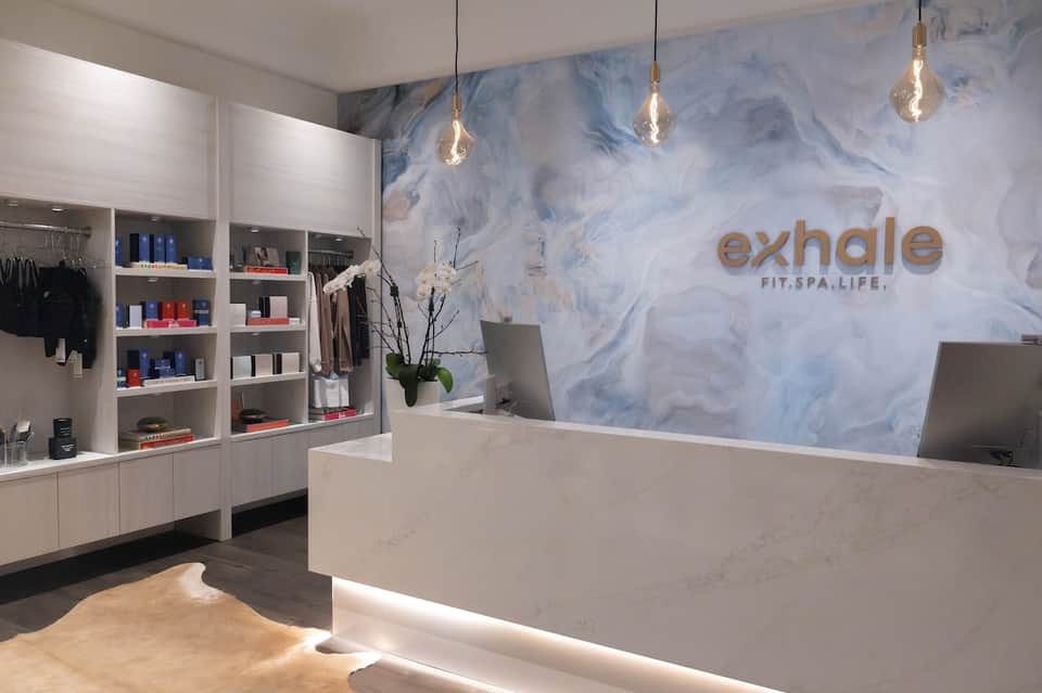 Modern spa reception desk with blue marble wall and product displays