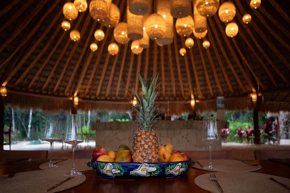 Fine dining table setup under elegant dome with golden pendant lights and fresh pineapple centerpiece
