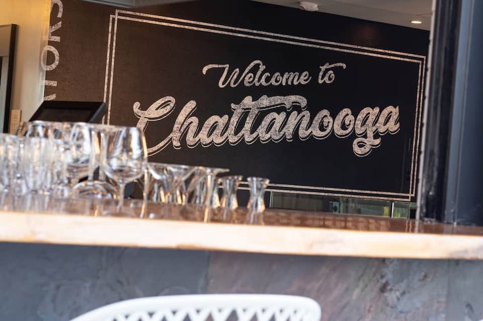 Hotel reception desk with welcome sign reading 'Welcome to Chattanooga' and glassware display