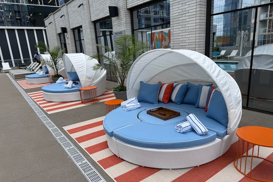 Modern rooftop lounge with blue pod chairs, white canopy, and striped rug