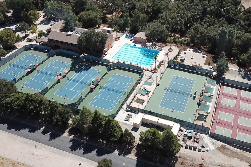 Aerial view of resort with Olympic swimming pool, tennis courts, and surrounding forested landscape