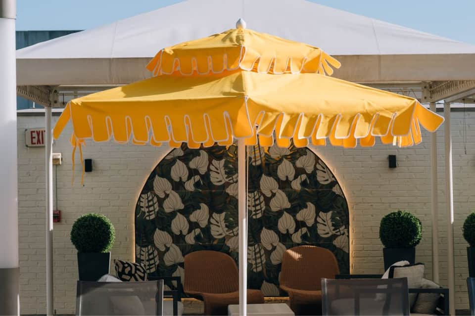 Restaurant patio with yellow scalloped umbrellas, patterned backdrop, and outdoor dining setup