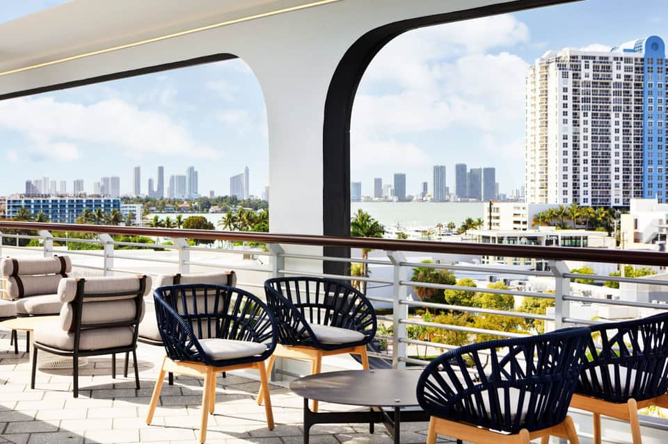 Waterfront balcony with modern seating overlooking city skyline and bay with palm trees