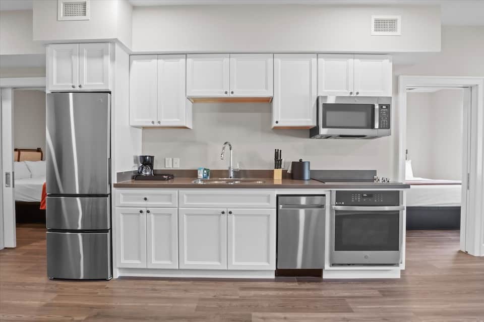 Modern kitchen with white cabinetry, stainless steel appliances, and wood countertops