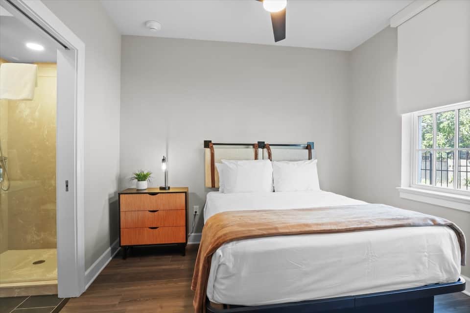 Contemporary bedroom with orange nightstand, modern headboard, and en-suite bathroom