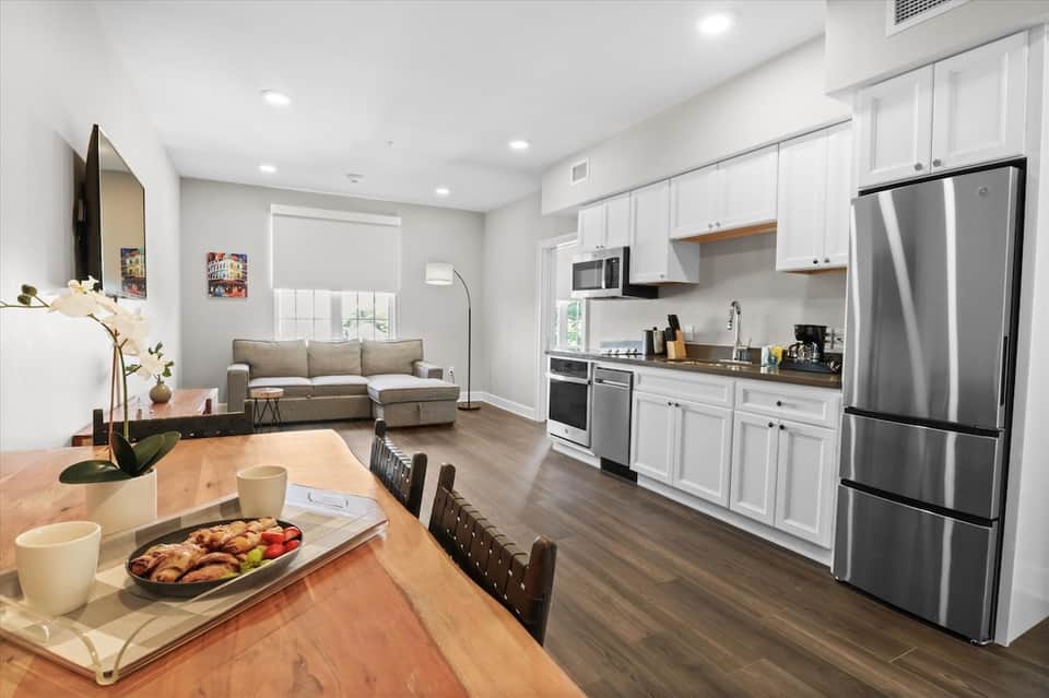 Modern hotel suite kitchen and living area with stainless steel appliances and hardwood floors