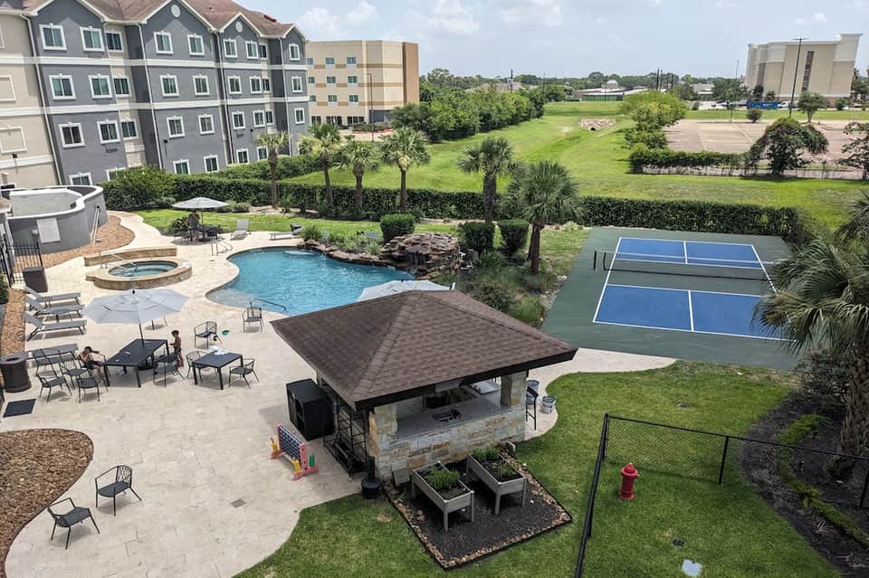 Resort courtyard with pool, spa tub, picnic area, tennis courts, and green landscape views