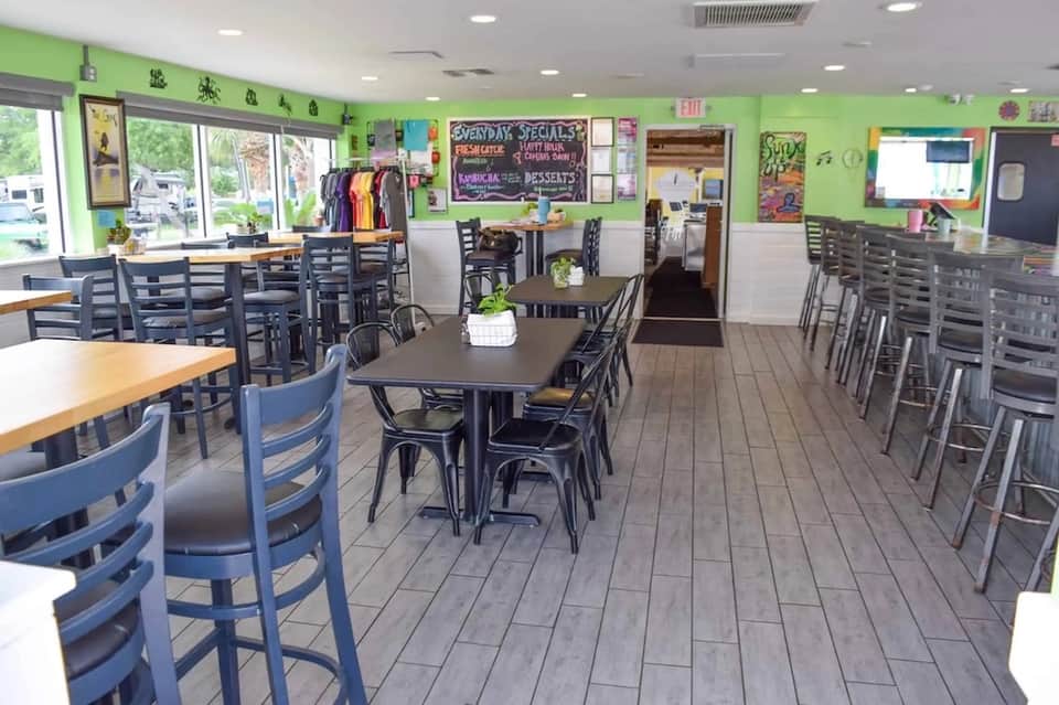 Casual dining area with green walls, black chairs, and display cases