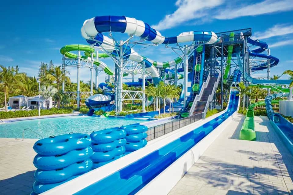 Water park with blue and green slides, lazy river tubes, and palm trees
