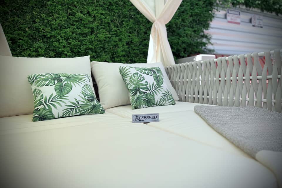 Reserved outdoor lounge seating with green leaf patterned pillows and white canopy