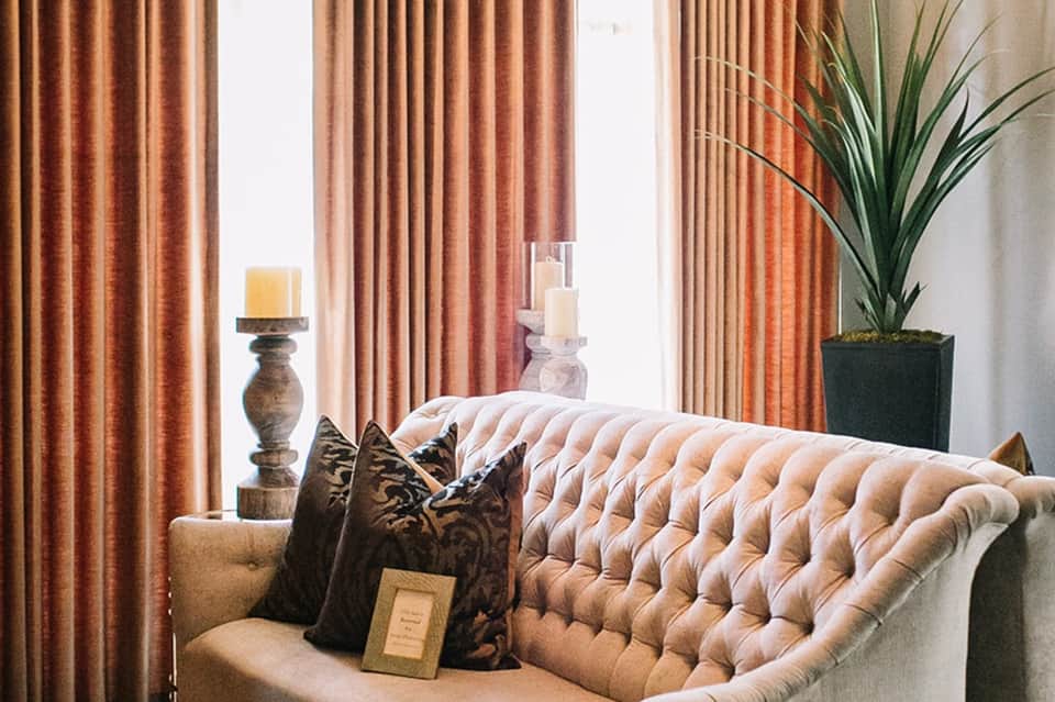 Luxury suite interior with tufted sofa, terracotta curtains, and decorative pillows