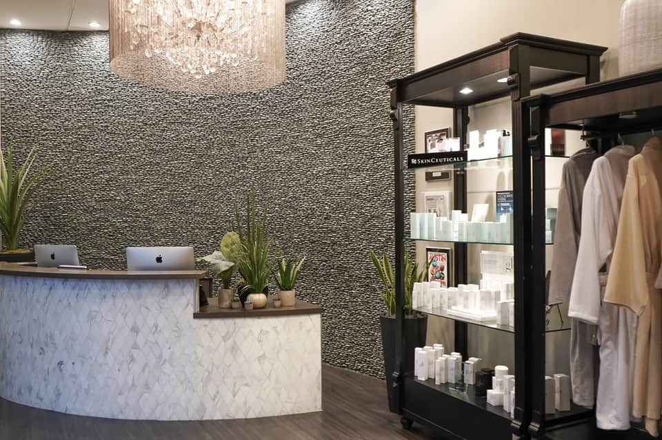 Luxury spa reception area with marble counter, textured wall, and product display shelves