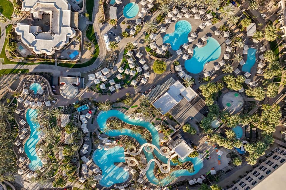 Aerial view of sprawling resort with multiple pools and palm tree landscaping