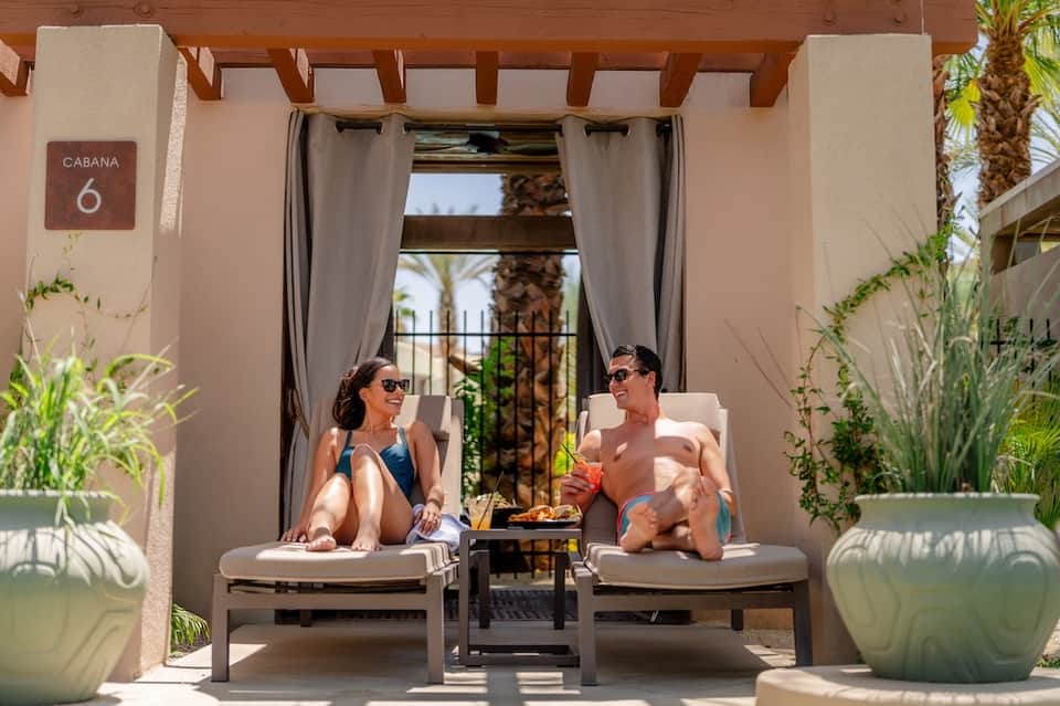 Couple relaxing in private cabana lounge chairs with ocean view and potted plants