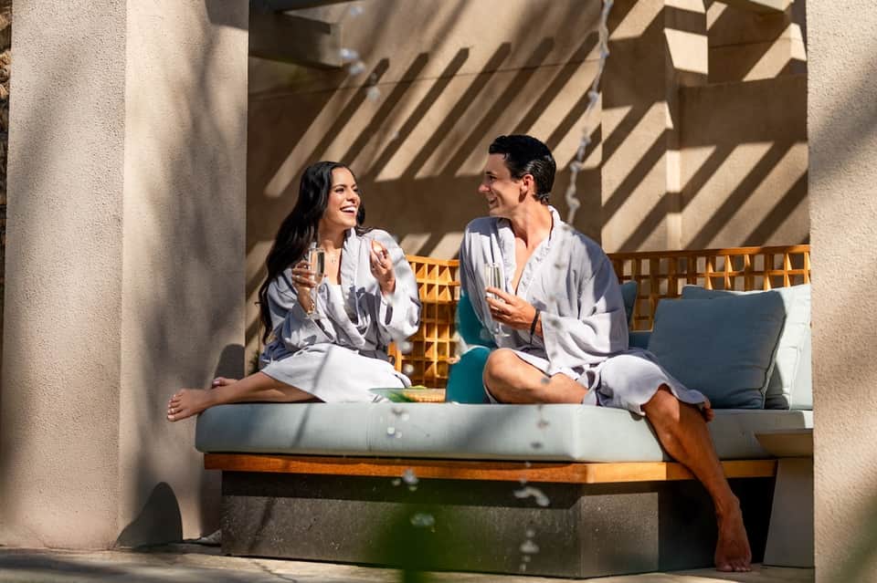 Couple enjoying drinks on sunny terrace with architectural shadow details