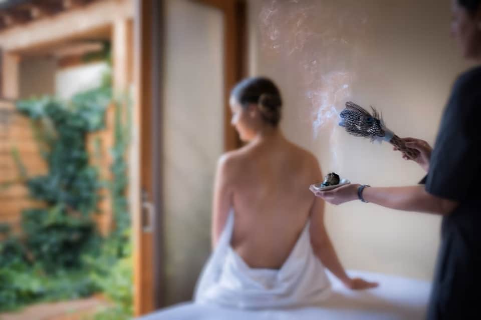 Spa attendant applying treatment to shirtless client's back in serene indoor wellness setting