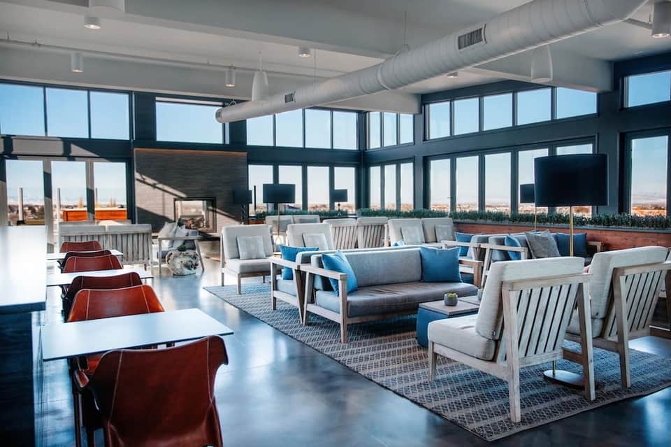 Modern rooftop lounge with floor-to-ceiling windows, contemporary furniture, and city skyline views