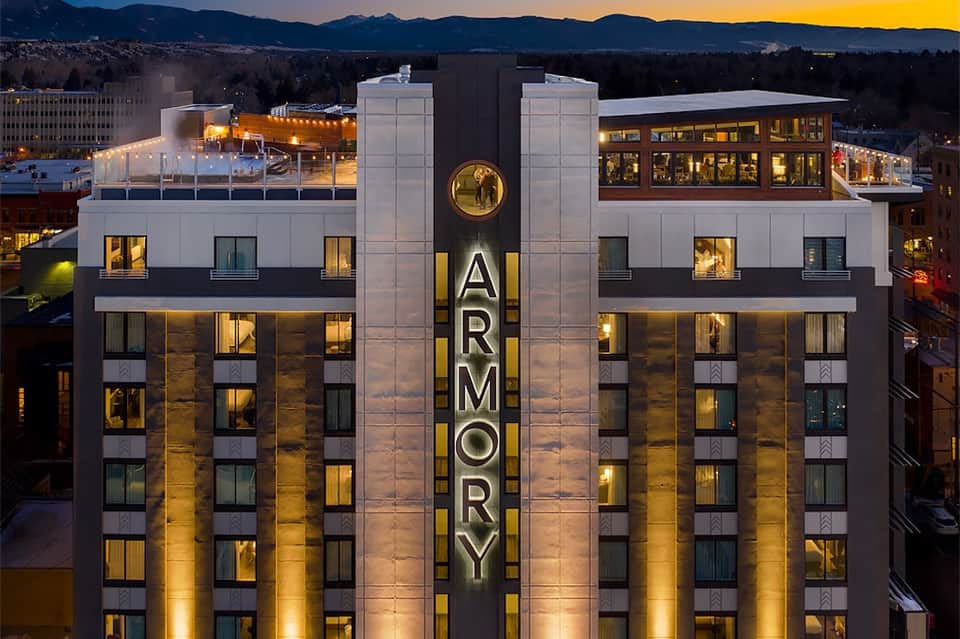 The Armory hotel building at night with historic facade, lit windows, and mountain backdrop