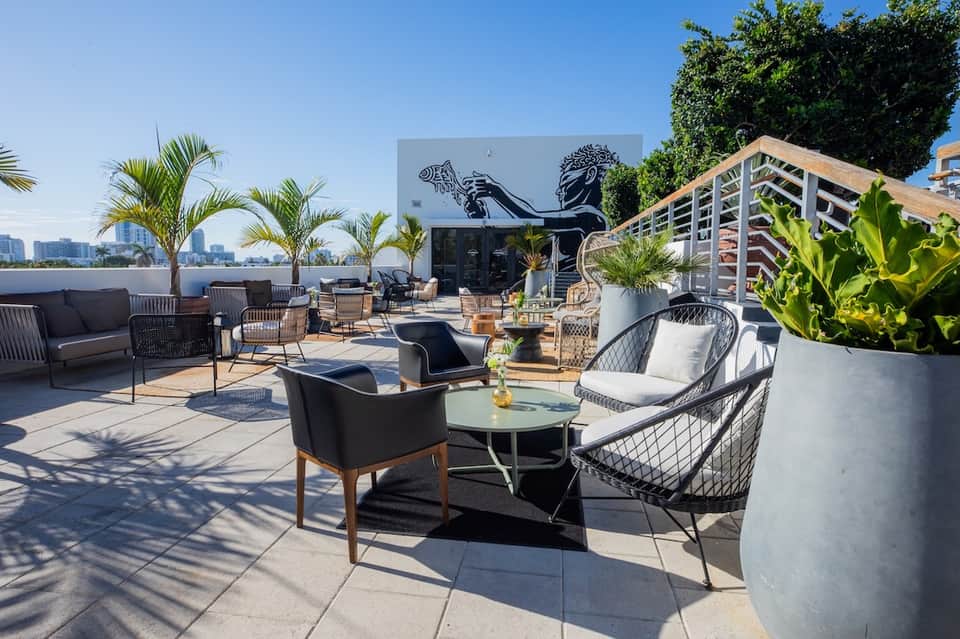 Rooftop terrace with modern seating, tropical plants, ocean views, and contemporary design