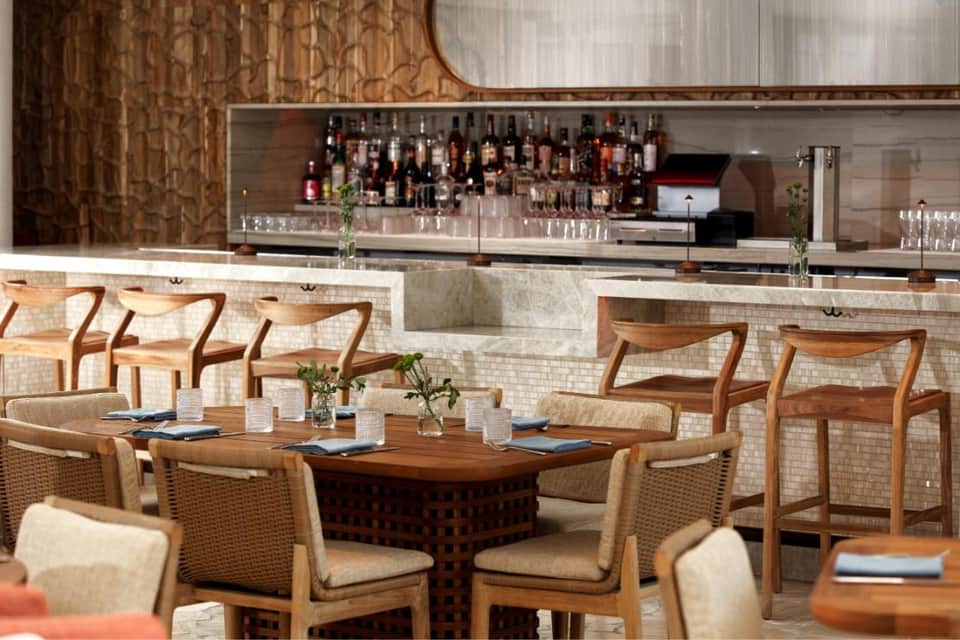 Upscale bar restaurant with wooden chairs, stone accents, and extensive liquor display