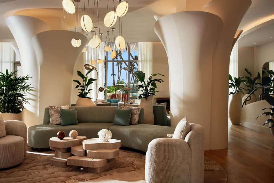 Elegant modern lobby with curved columns, pendant lighting, green sofa, and potted plants